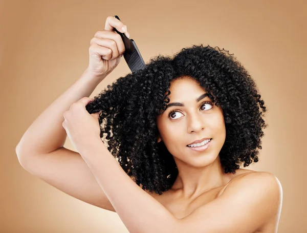 Hair care, afro and woman with a comb, beauty and treatment on a brown background. Person, girl and model with salon grooming, volume or shine with glow, wellness and aesthetic with texture and clean.