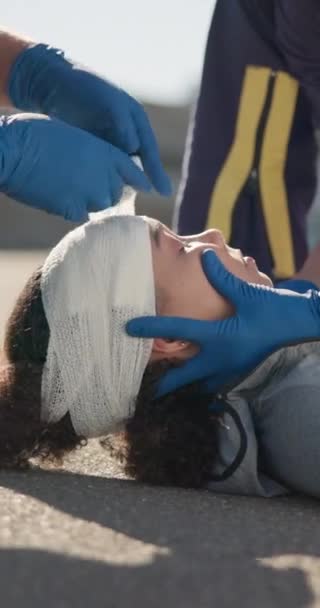 救急隊 救急隊員の手 女性への包帯 頭部の怪我 緊急事態 ストリートアウトドアでの医療 ヘルスケア ヘルプ 救助のためのアラブ患者のクローズアップ 医療チームとドレッシング — ストック動画