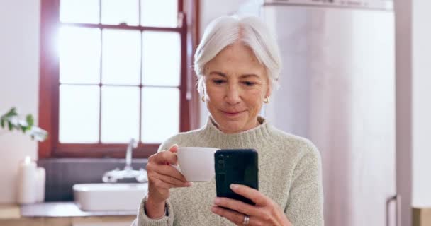ソーシャルメディア インターネットスクロール リラックスしたテクノロジーのためのキッチンでのシニア 高齢者 スマートフォン ウェブサイトでのストリーミング — ストック動画