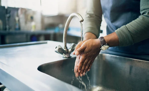 Water, safety and washing hands in the kitchen with a person by the sink for skincare or wellness. Cleaning, hygiene and bacteria with an adult closeup in the home to rinse for skin protection.
