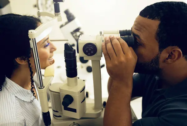 Eye test, machine and a woman with a doctor for a service, vision problem and surgery on lens. Happy, clinic and a patient with a man or optometrist for a medical exam, retina health and check.