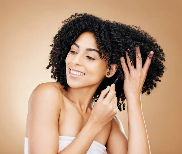 Afro, hair and comb of woman in studio with healthy coil texture, natural growth or cosmetics on brown background. Happy model, curly haircare tools or brush for salon aesthetic, care or clean beauty.