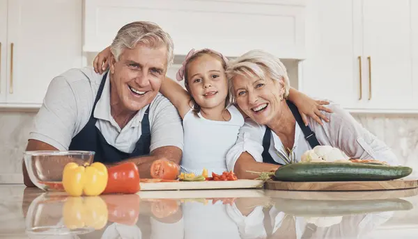 Family, portrait and girl cooking with grandparents in a kitchen with love, hug or support at home. Food, face and child learning nutrition, health or preparing meal while embracing happy old people.