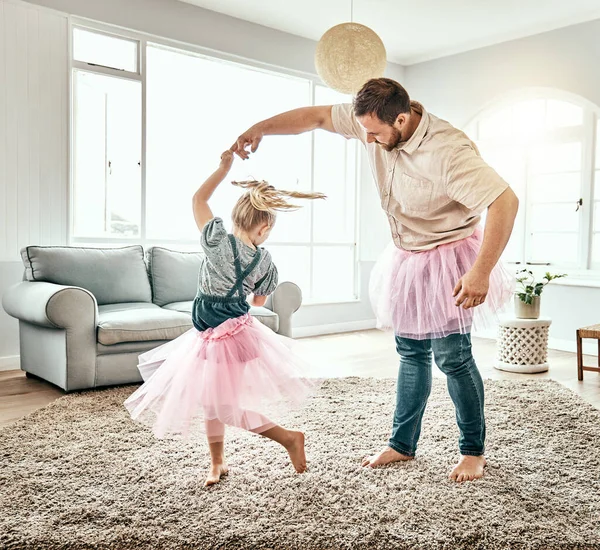 Family, dance or ballet with a father and daughter together in costume, having fun in the home living room. Love, kids or fantasy and a girl child dancing with her man parent on a carpet in the house.