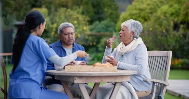コーヒーのためのカップルとの話し合い 庭と看護師 ハッピー テーブル 女性介護者 ランチ 食べ物 自然の中で高齢者と女性 — ストック動画