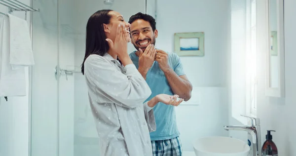 Couple, bathroom and cleaning face for skincare, routine and comic joke with cream, serum and product. Man, woman and funny with facial oil moisturiser for health, wellness and self care in apartment.