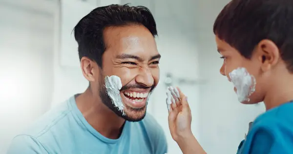 Shaving, bathroom and father teaching child about grooming, playing hygiene and facial routine. Playful, help and dad showing boy kid cream or soap for hair removal together in a house in the morning.