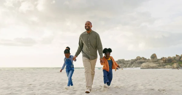 Walking, father and children holding hands at the beach for bonding, summer freedom and care. Happy, family and an African dad with affection for kids on a walk in the sand at the ocean on holiday.