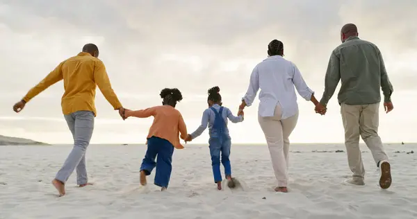 Happy, love and holding hands with black family at beach for summer, vacation and relax. Holiday, support and travel with parents and children walking on coastline for care, trust and freedom.