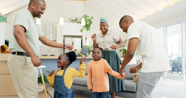 Moving, boxes and parents with kids dancing in living room of new house, happiness and investing in home. African mother, father and children with cardboard box, real estate and happy black family