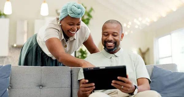 Black couple, laughing and tablet on a home sofa for streaming, meme and internet in a living room. African woman and man together to talk about tech, funny post or video on social media or network.