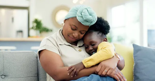 Mother hug sleeping child on couch for love, care or holding for comfort in lounge at home. Black woman, happy mom and kissing girl kid on lap for nap, rest or support to relax on sofa in living room.