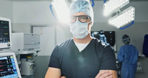 Surgeon, doctor and man in portrait with arms crossed, healthcare and confidence in operation theater for medical procedure. Surgery, health professional and help in hospital, expert with face mask.