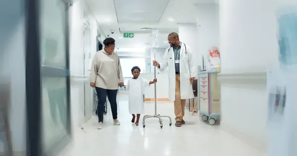 Medical, pediatrician and a doctor walking with a black family in a hospital corridor for diagnosis. Healthcare, communication and consulting with a medicine professional talking to a boy patient.