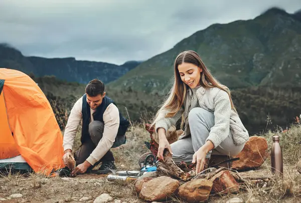Happy couple, campfire and set up tent in nature for vacation, holiday and travel together. Camping, man and woman outdoor preparing for adventure, hiking and trekking in the countryside for freedom.