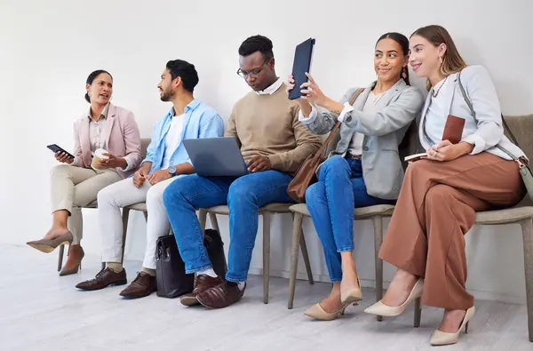 Group of people, waiting room and interview at job recruitment agency with laptop, tablet and resume. Human resources, hiring and business men and women in lobby together with career opportunity