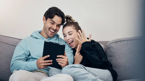 Man, woman and video call for engagement ring with happiness on sofa in living room of home. People, couple and couch with tablet and excited face for commitment goal and social media announcement.