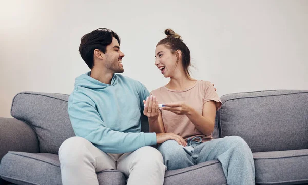 Pregnancy test, happy and couple in home living room, reading good news or check results. Kit, excited man and pregnant woman or mother smile on sofa for success, future maternity or ivf fertility.