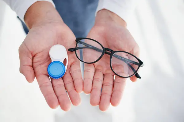 Eye care, hands of doctor with glasses and contact lens in case for vision, help with eyesight and choice. Eyecare, decision and sight, man giving lenses in container and frame for eyewear option