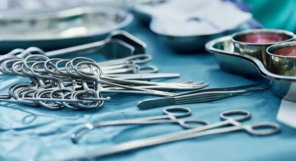 Background, surgery and metal tools in operating room for hospital assessment, healthcare service or emergency in medical theatre. Closeup, surgical equipment and scissors with forceps for operation.