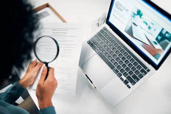 Magnifying glass, computer and woman reading cv in office for company recruitment website. Research, technology and closeup of female designer with hiring paperwork and laptop in workplace