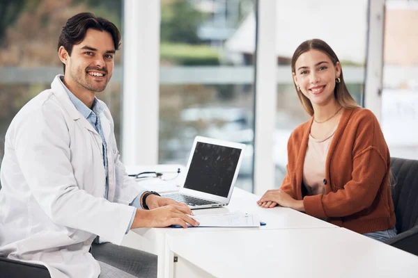 Doctor, man and woman with laptop in portrait, smile and documents for healthcare consulting in hospital office. Medic, patient and happy for results, report and computer with help, wellness or exam.