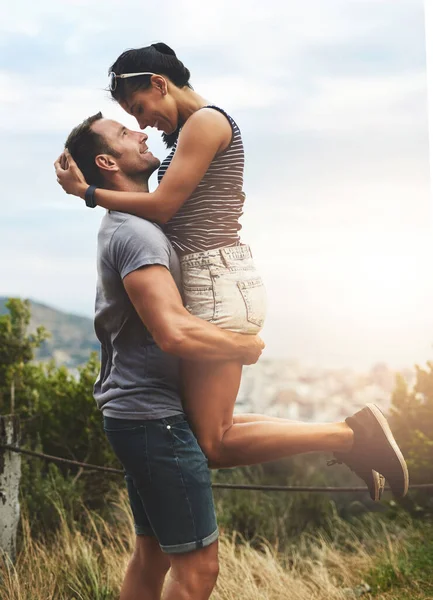 Love, lift or happy couple hug in park for date or care in nature with support, bond or freedom. Eye contact, romantic man or woman excited by holiday vacation together to celebrate, relax or travel.