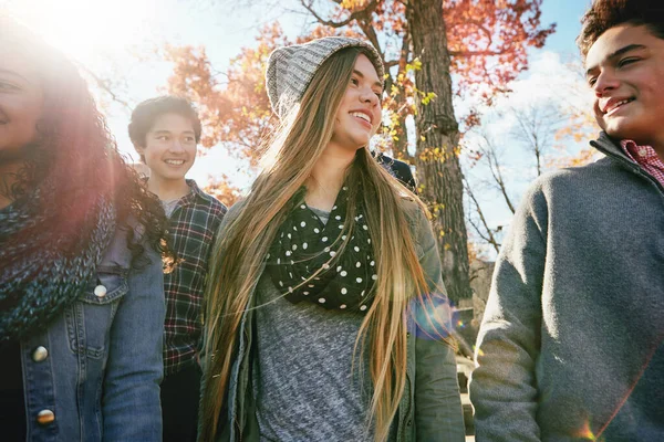 Teenager, walking and talking with friends in park, nature or social group outdoor in autumn with diversity. Happy, teens or kids relax in fall with a joke, best friend or conversation in community.