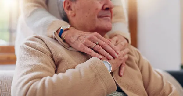 Hands, empathy and a senior couple closeup in their home for love, support or trust during retirement. Hope, healing and sympathy with elderly people on a sofa in the living room of their home.
