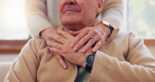 Hands, empathy and a senior couple closeup in their home for love, support or trust during retirement. Hope, healing and sympathy with elderly people on a sofa in the living room of their home.