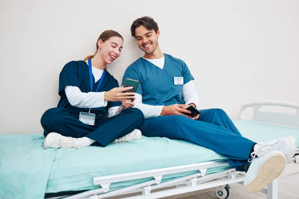 Doctor, student phone and friends on break with laughing on a hospital, healthcare and clinic bed with social media. Smile, mobile and happy young people with rest from medical and nursing internship.