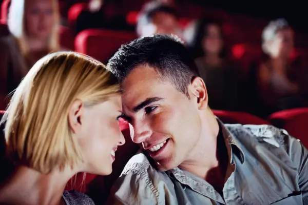 Cinema, date and happy couple watching movie, smile and romantic night together for show. Theater, man and woman with love, trust and care sitting in auditorium audience to relax at film premier.