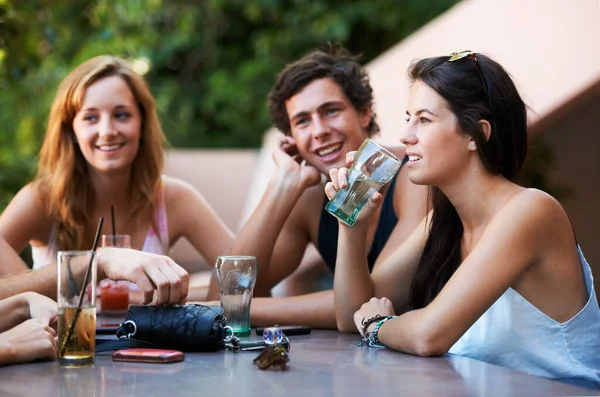 Friends, bar and drinks during conversation on the weekend for bonding, happiness and social. Table, alcohol and people, men or women speaking at an outdoor restaurant for a group chat or drinking.