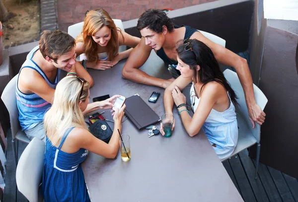 Smartphone, smile and group with conversation, restaurant and social media with gathering, bonding and relax. People, men and women with a cellphone, cafe and outdoor with fun, discussion or chatting.