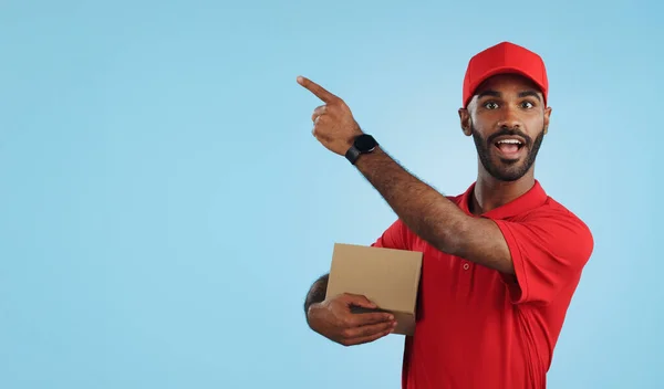 Advertising studio smile, delivery man and point at supply chain commercial, discount export info or distribution schedule. Courier service deal, mockup space and portrait person on blue background.