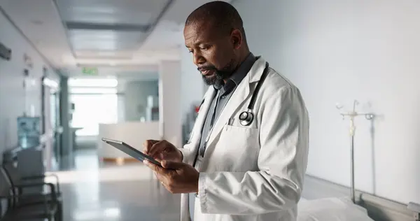 Doctor, hospital and tablet of healthcare information, typing and management of online charts or results. Healthcare worker or african person smile for service, planning or data on digital technology.