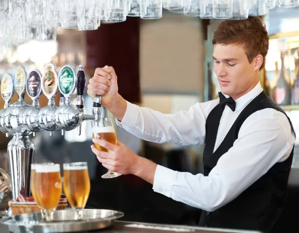 Man, bartender and waiter with beer at pub, restaurant or event for happy hour, hospitality industry or customer service. Young barman, server or catering employee with alcohol drinks in glasses.