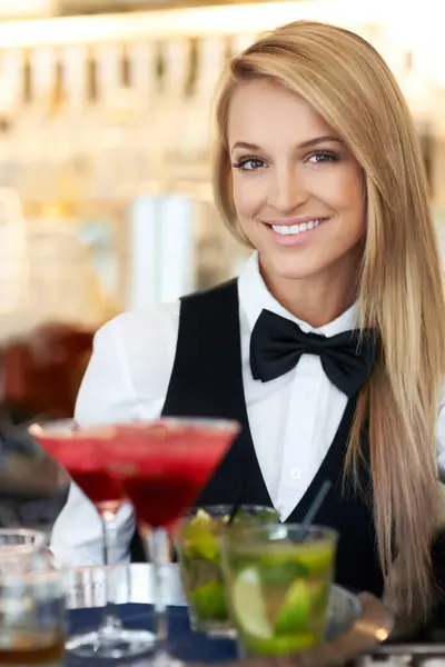Woman, bartender and waitress with cocktails at restaurant for happy hour, hospitality industry or customer service. Portrait of happy worker, server or catering employee with alcohol drinks in glass.