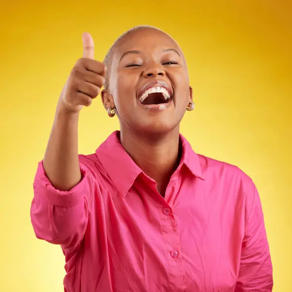 Laughing, black woman and thumbs up in studio for vote, review or positive feedback on yellow background. Yes, hand and happy African female with emoji for choice, thank you or decision support.