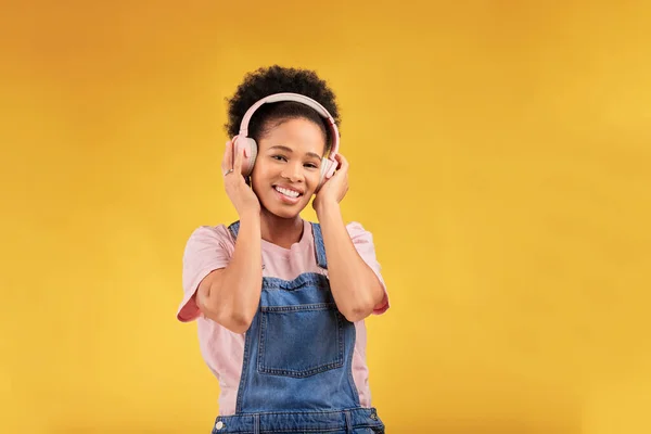 Headphones, music and black woman in portrait, smile and isolated in studio on a yellow background mockup space. Face, happy and person listening to radio, podcast or sound for jazz, hip hop or audio.