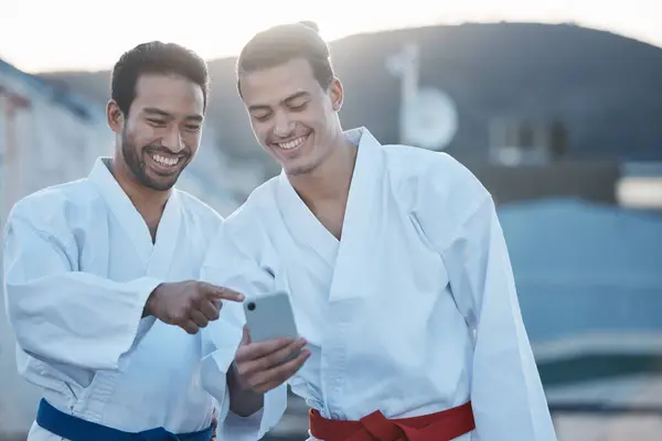 Men, martial arts or karate class with phone, thinking or pointing at training video on web for development. Fight workout partnership, smartphone or meme with focus for exercise, coaching or sports.