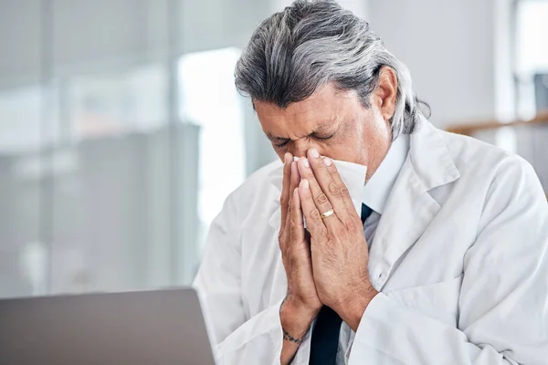 Man, blowing nose and senior doctor sick with allergy, covid or virus in hospital or clinic. Elderly medical professional, tissue and allergies for health problem, cold fever and bacteria in winter.