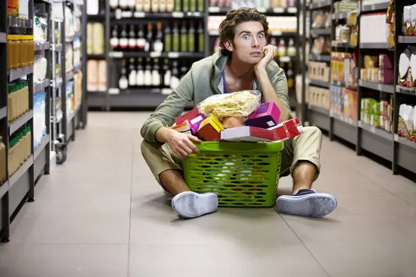 Man, grocery shopping and supermarket, stress about inflation and expensive food, overwhelmed in store. Groceries in basket, retail and customer shocked by price, choice and purchase with fear.