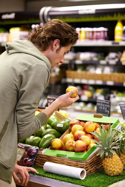 Man, choice and fruit, grocery shopping and store with fresh produce, retail and customer look at product. Groceries, food and nutrition, back or buying with decision, market and client in shop.