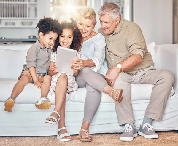 Social media, children and grandparents with tablet in a house, streaming cartoon or movie online. App, smile and interracial kids and senior man and woman with technology for a film, game or website.