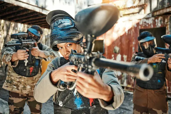 Paintball team, gun and woman focus on player challenge, target aim or military conflict, fight or soldier mission. Group, serious or people pointing weapon in survival war, action or battle training.