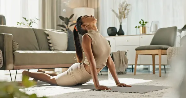 Home, yoga and woman stretching back on floor in living room with peace in apartment. Holistic, exercise and girl workout for zen mindfulness, wellness and breathing for mental health or stress.