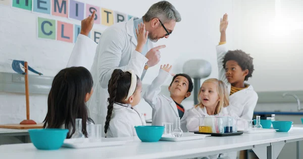 Science, question and students in class with their teacher for learning or to study chemistry. Children, hands raised and education with kids in a laboratory for an experiment of chemical reaction.