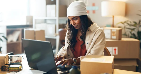Woman, laptop and typing in small business logistics for order, ecommerce or design at boutique. Female person, tailor or fashion designer on computer for inventory, storage or inspection at store.