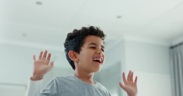 男孩和跳在床上在家里 同时玩有趣的游戏与精力 自由和笑 一个兴奋 活泼的小孩的脸在屋里的家具上跳着 欢快地移动着 — 图库视频影像
